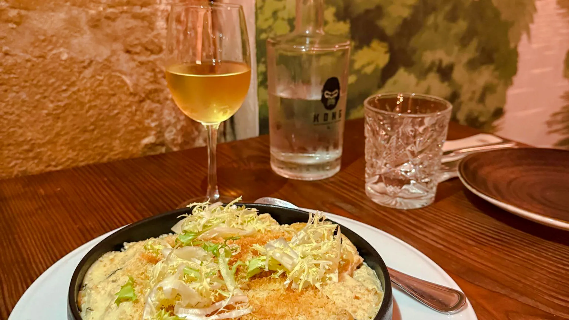 Vegan dish with greens and a glass of white wine on a Lisbon food tour.