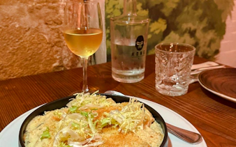 Vegan dish with greens and a glass of white wine on a Lisbon food tour.