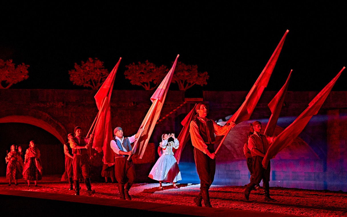 Performers with flags in a night scene from "El Sueño de Toledo" show.