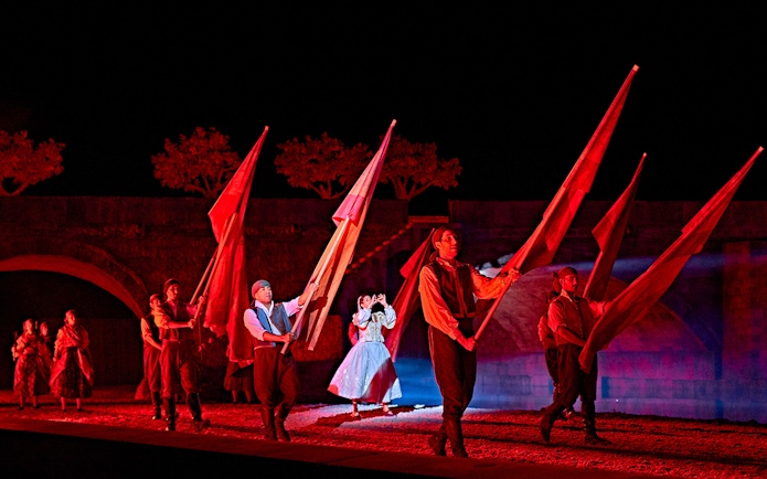 Performers with flags in a night scene from "El Sueño de Toledo" show.