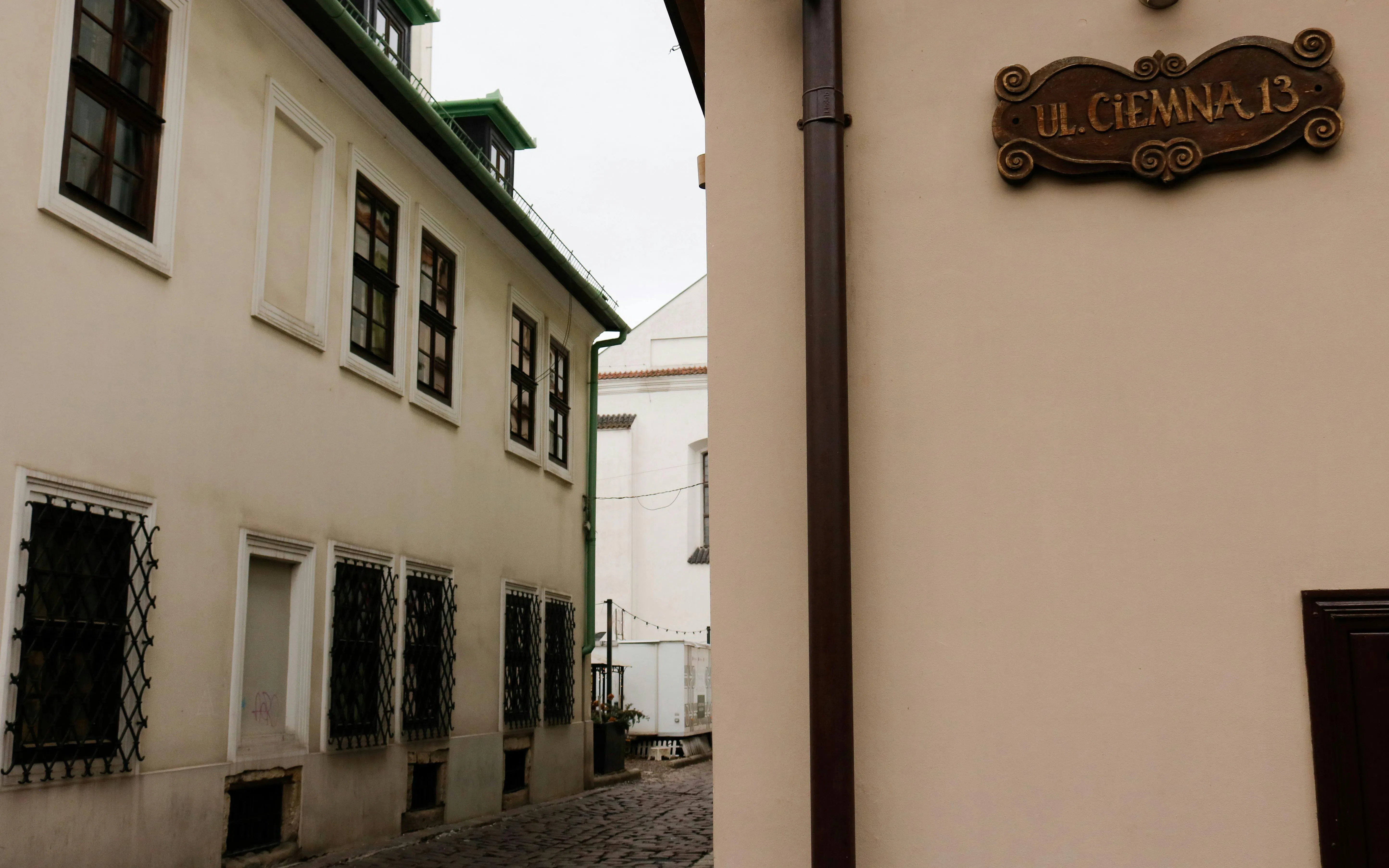 Narrow street in Krakow's Kazimierz district with historic buildings and a street sign.
