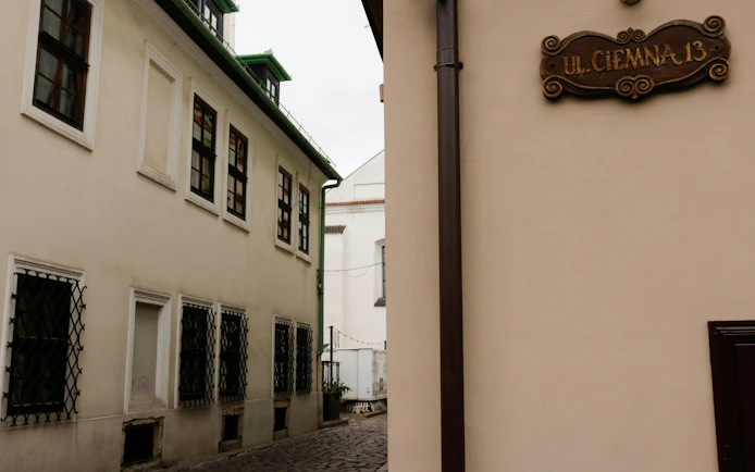 Narrow street in Krakow's Kazimierz district with historic buildings and a street sign.