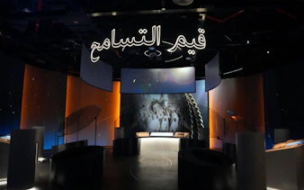 Exhibit at Light & Peace Museum, Sheikh Zayed Grand Mosque Centre, featuring illuminated Arabic script.