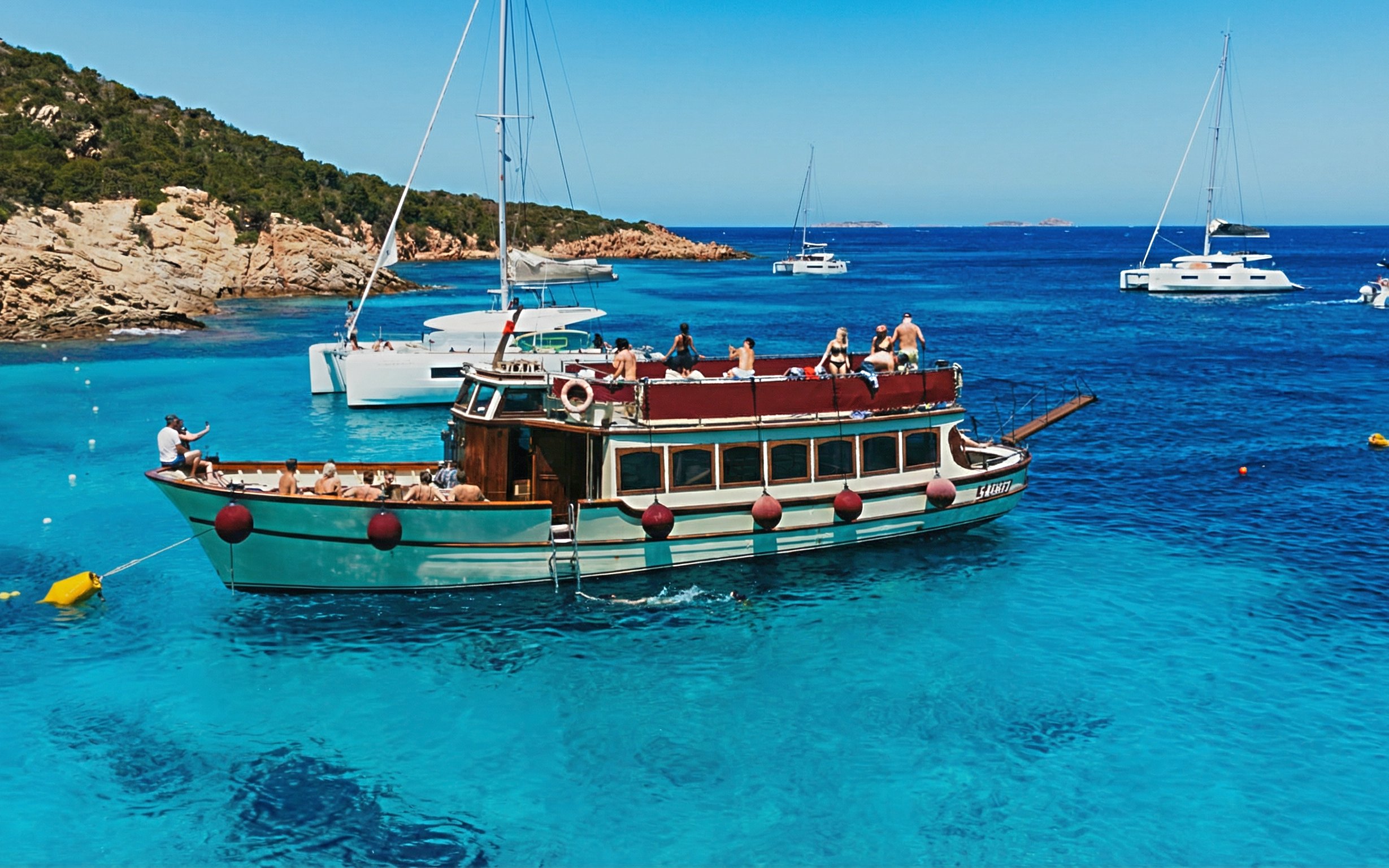 Motorboat tour in La Maddalena Archipelago with passengers enjoying the view.