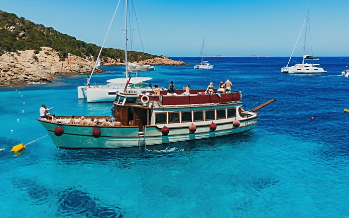 Motorboat tour in La Maddalena Archipelago with passengers enjoying the view.