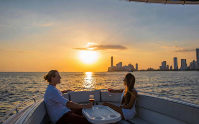 Tourists enjoying a sunset boat party in Cartagena Bay with city skyline.
