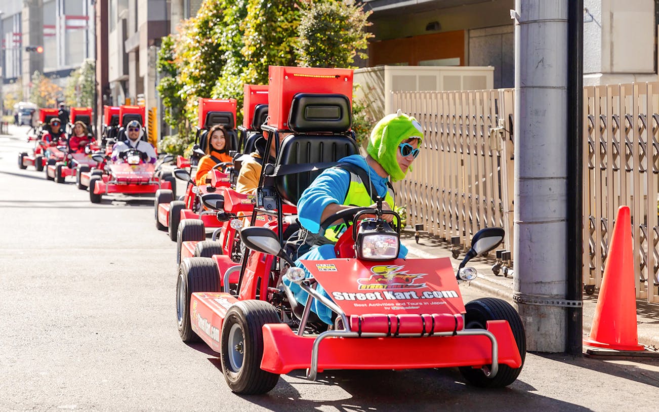 Tourists in costumes driving go karts during Shibuya Go Karting experience in Tokyo.
