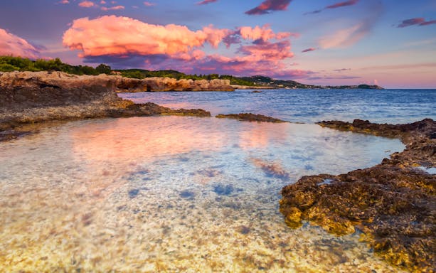 Argostoli coastline at sunset with vibrant clouds reflecting on the sea, Greece.