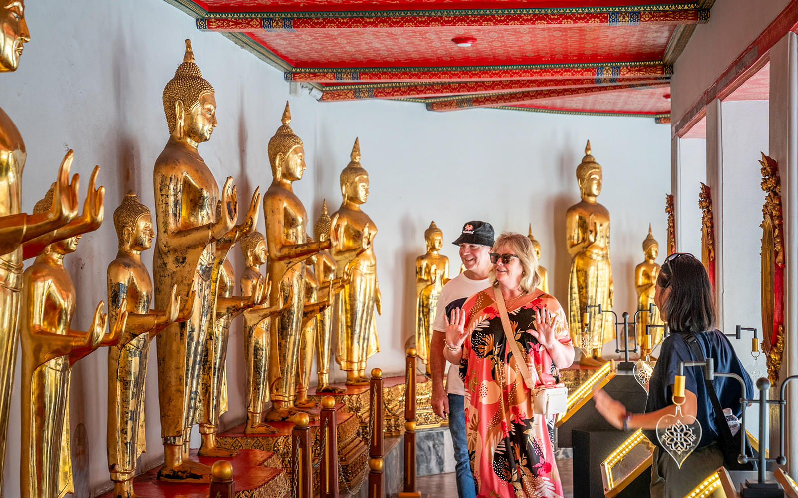 Tourists exploring golden Buddha statues at Wat Pho, Bangkok.