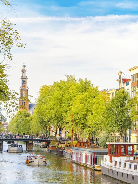 Canal view with boats and Westerkerk tower in Amsterdam Red Light District.