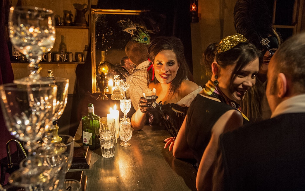 Visitor enjoying a drink at a candlelit bar in London Dungeon.
