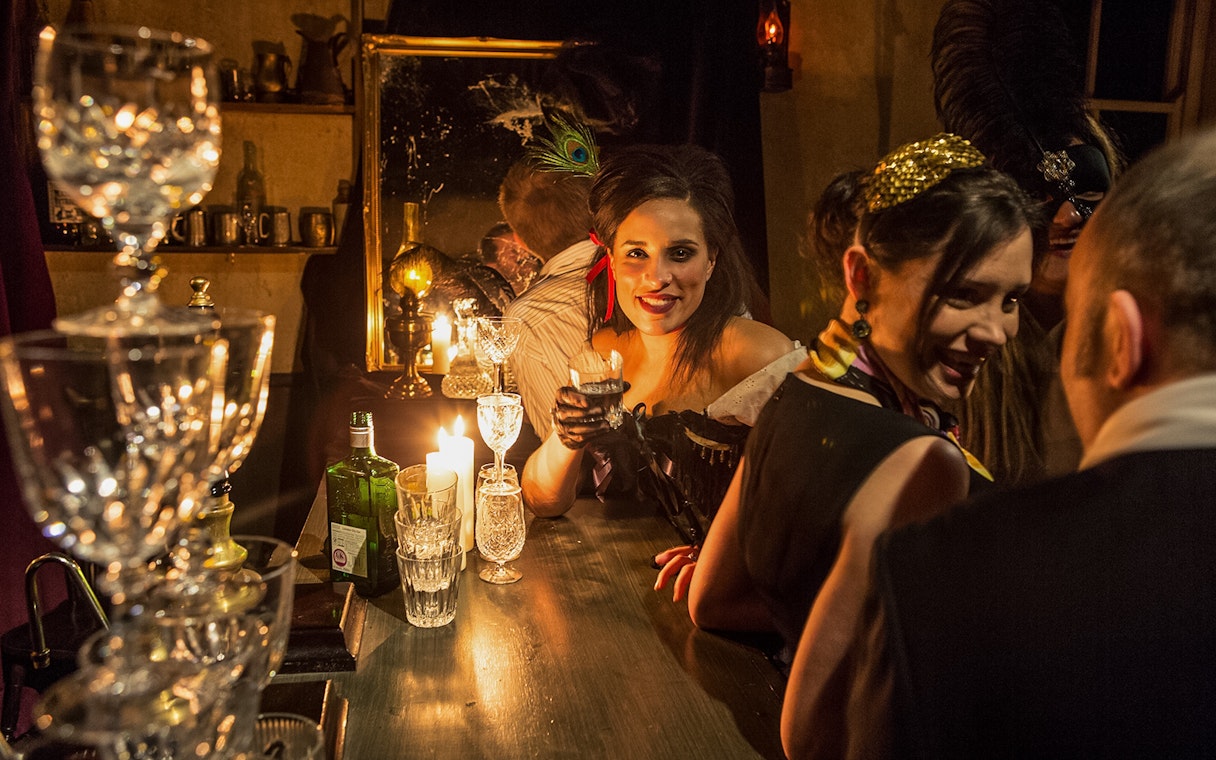 Visitor enjoying a drink at a candlelit bar in London Dungeon.
