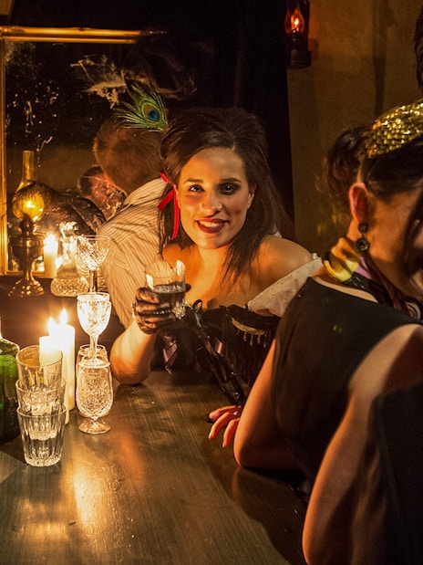Visitor enjoying a drink at a candlelit bar in London Dungeon.
