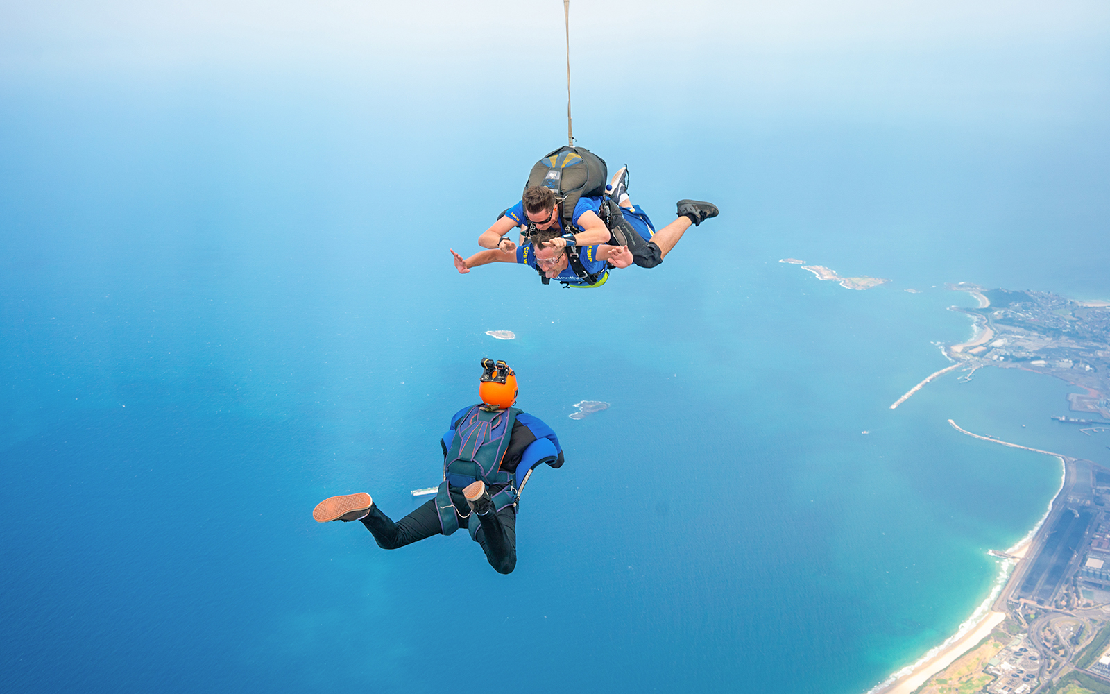 Tandem skydivers freefalling over Wollongong coastline near Sydney.