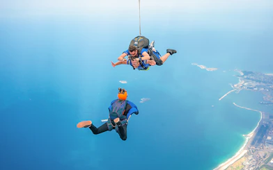 Tandem skydivers freefalling over Wollongong coastline near Sydney.