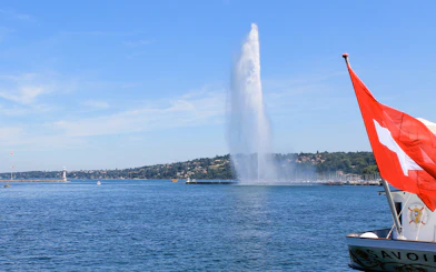 Jet d'Eau fountain on Lake Geneva with Swiss flag in foreground.