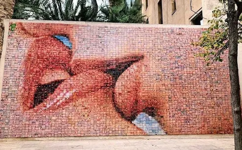 Mosaic mural of kissing lips in Barcelona, part of a self-guided city exploration game.
