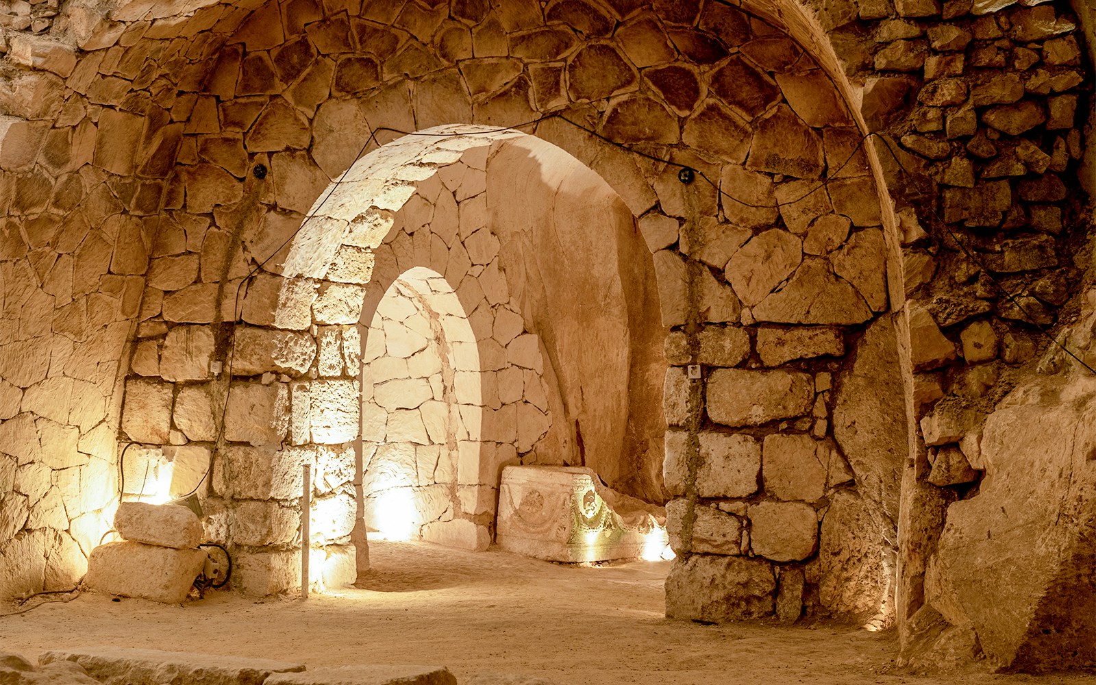 Ancient stone arches in the illuminated Rome Catacombs.