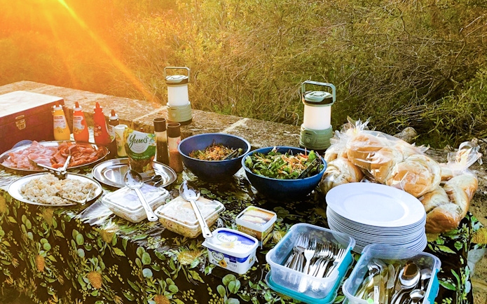 Outdoor picnic setup with salads, bread, and condiments for Pinnacles Sunset & Stargazing Tour lunch.