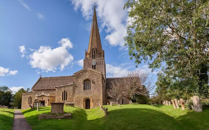 St Mary's Church in Bampton with its tall spire and surrounding graveyard.