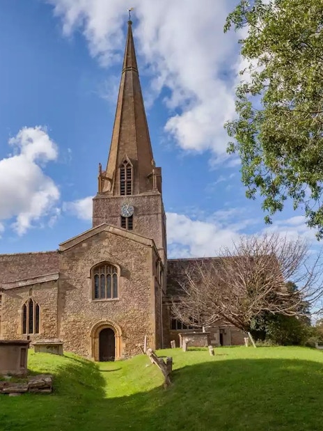 St Mary's Church in Bampton with its tall spire and surrounding graveyard.
