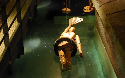 Wooden diving suit model in water at Leonardo da Vinci Museum exhibit.