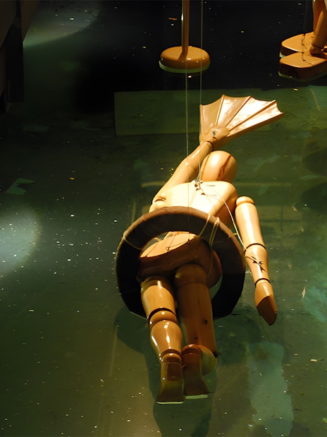 Wooden diving suit model in water at Leonardo da Vinci Museum exhibit.