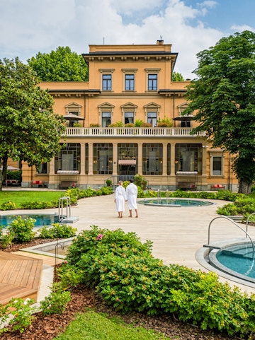 Couple in robes walking by pools at QC Terme Torino spa.