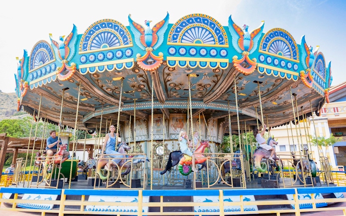 Carousel ride at Terra Mitica Benidorm with colorful decorations and people enjoying the attraction.