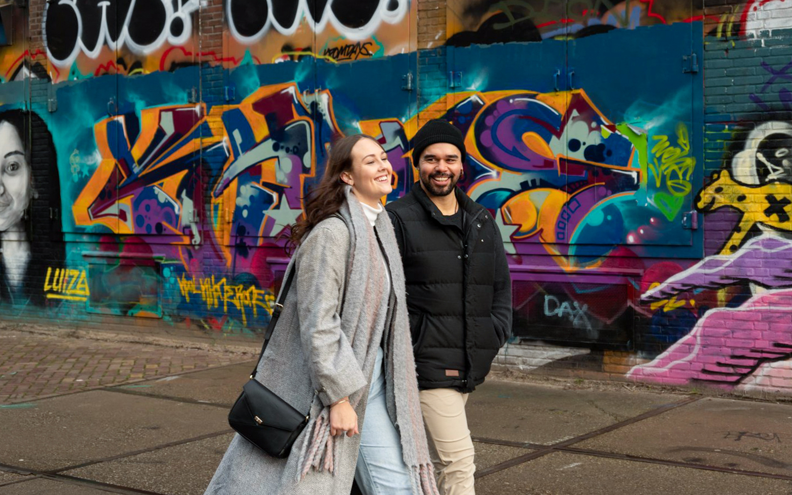 Couple walking by colorful graffiti at NDSM, Amsterdam during a professional photoshoot.
