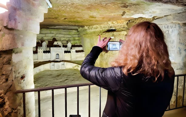 Woman photographing Catacombs of Paris model with smartphone.