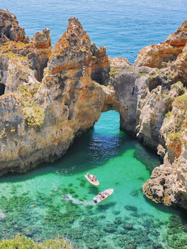 Kayakers exploring rock formations in the ocean, Lagos, Algarve.