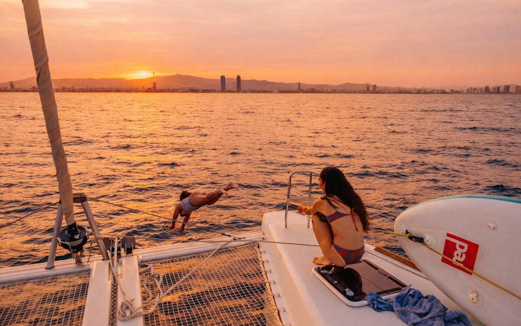 Tourist diving from yacht at sunset in Barcelona.