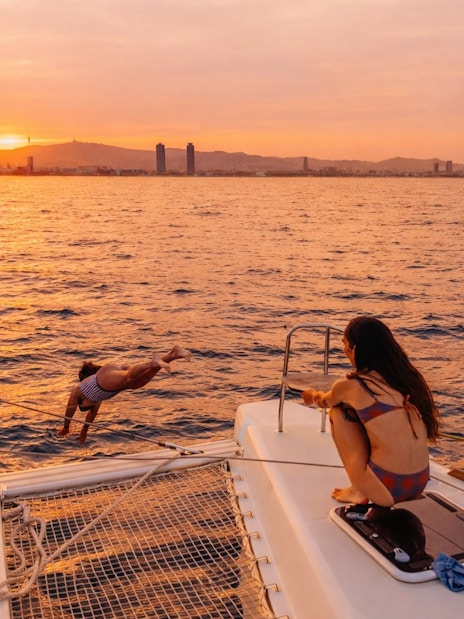 Tourist diving from yacht at sunset in Barcelona.