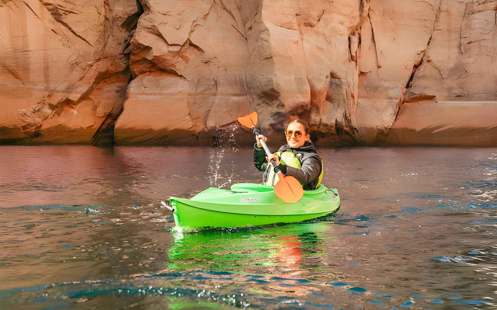 Woman kayaking on Lake Powell near Antelope Canyon's sandstone cliffs.