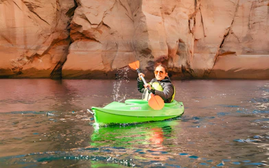 Woman kayaking on Lake Powell near Antelope Canyon's sandstone cliffs.