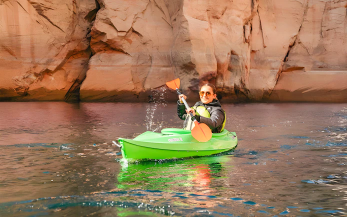Woman kayaking on Lake Powell near Antelope Canyon's sandstone cliffs.