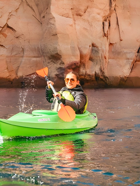 Woman kayaking on Lake Powell near Antelope Canyon's sandstone cliffs.