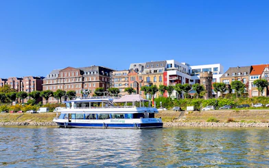 Cruise boat on the Rhine River with Cologne skyline in the background.