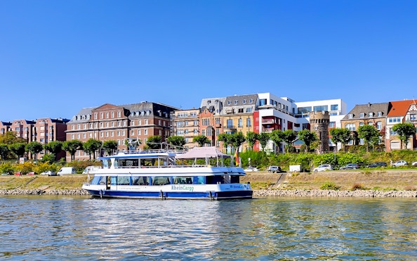 Cruise boat on the Rhine River with Cologne skyline in the background.