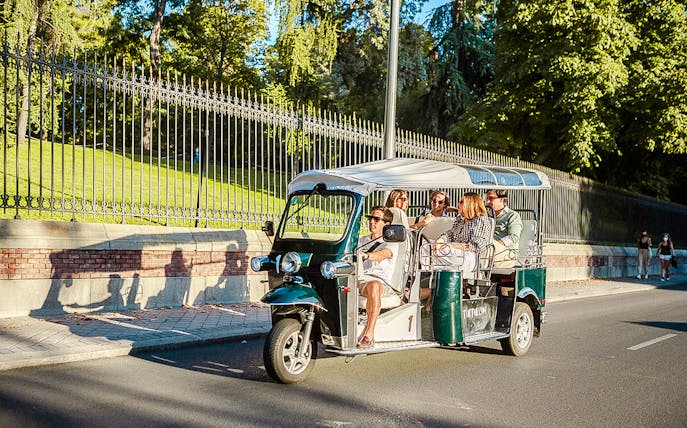 Lisbon Eco Tuk Tuk tour passing by historic tram and colorful buildings.