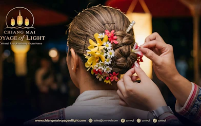 Woman's hair adorned with colorful flowers during Chiang Mai Voyage of Light festival.