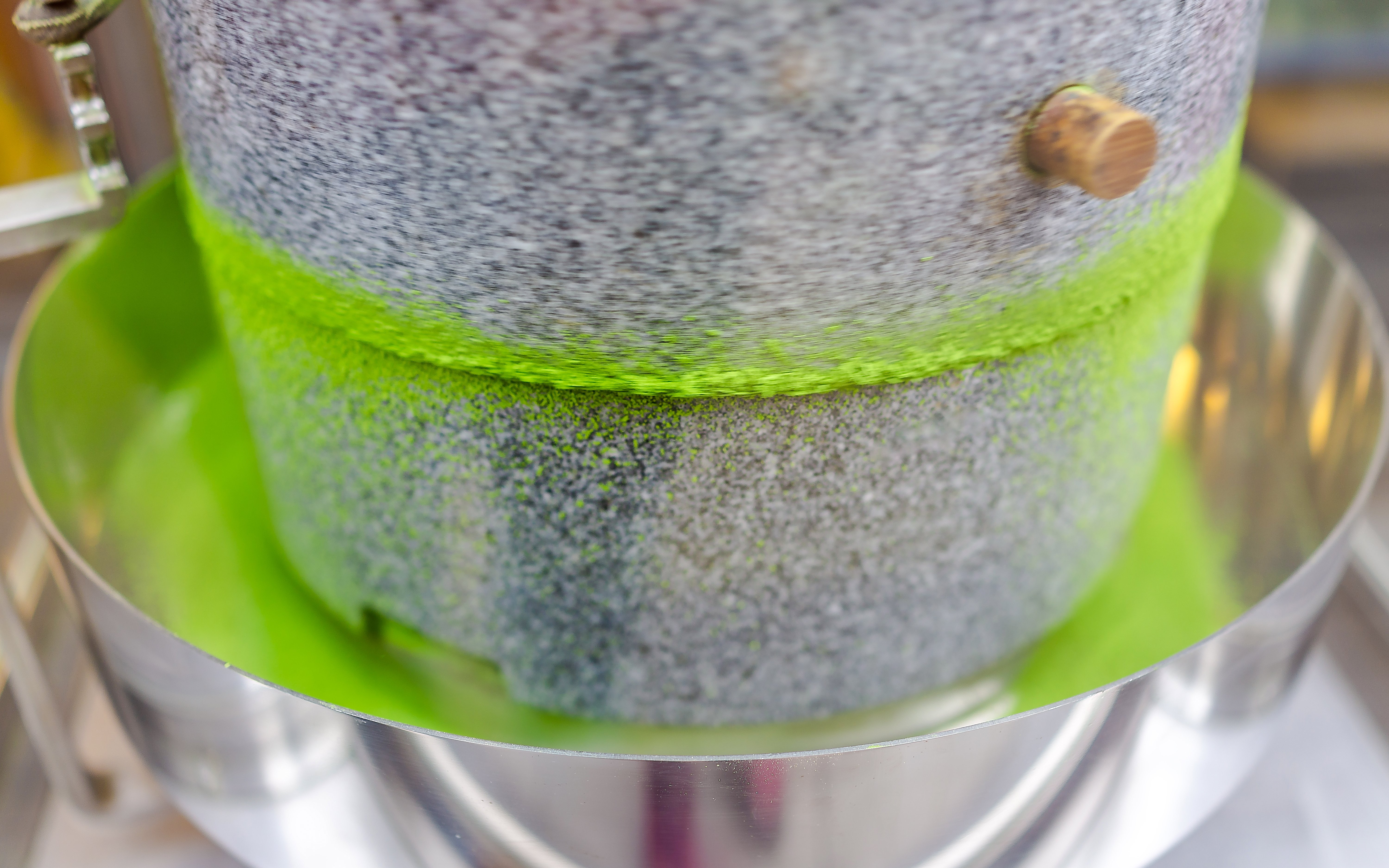 Grinding stone machine producing vibrant matcha green tea powder.