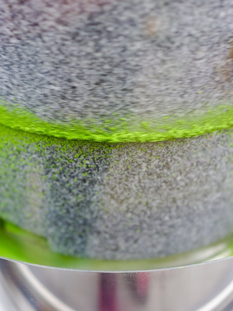 Grinding stone machine producing vibrant matcha green tea powder.