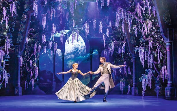 Performers dancing in a scene from Disneys Die Eiskönigin with a moonlit backdrop.