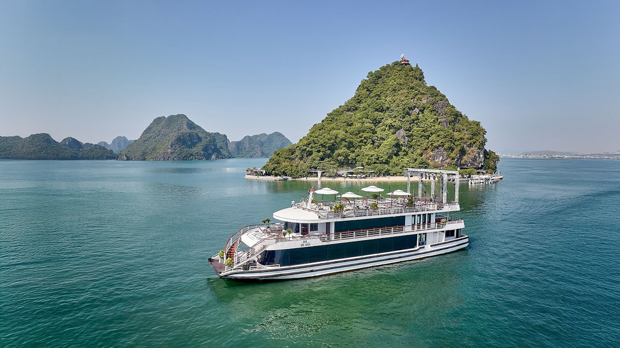 Cruise ship sailing in Ha Long Bay with limestone islands in the background.