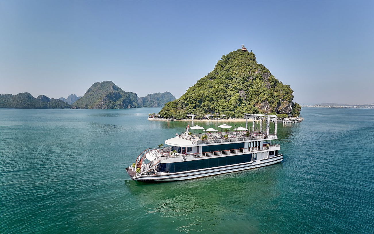 Ha Long Bay 5-Star Cruise ship sailing past limestone karsts and emerald waters in Vietnam.
