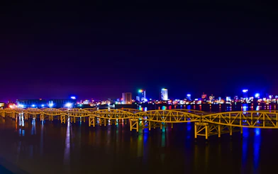 Night view of illuminated bridge over river with Da Nang city skyline in the background.