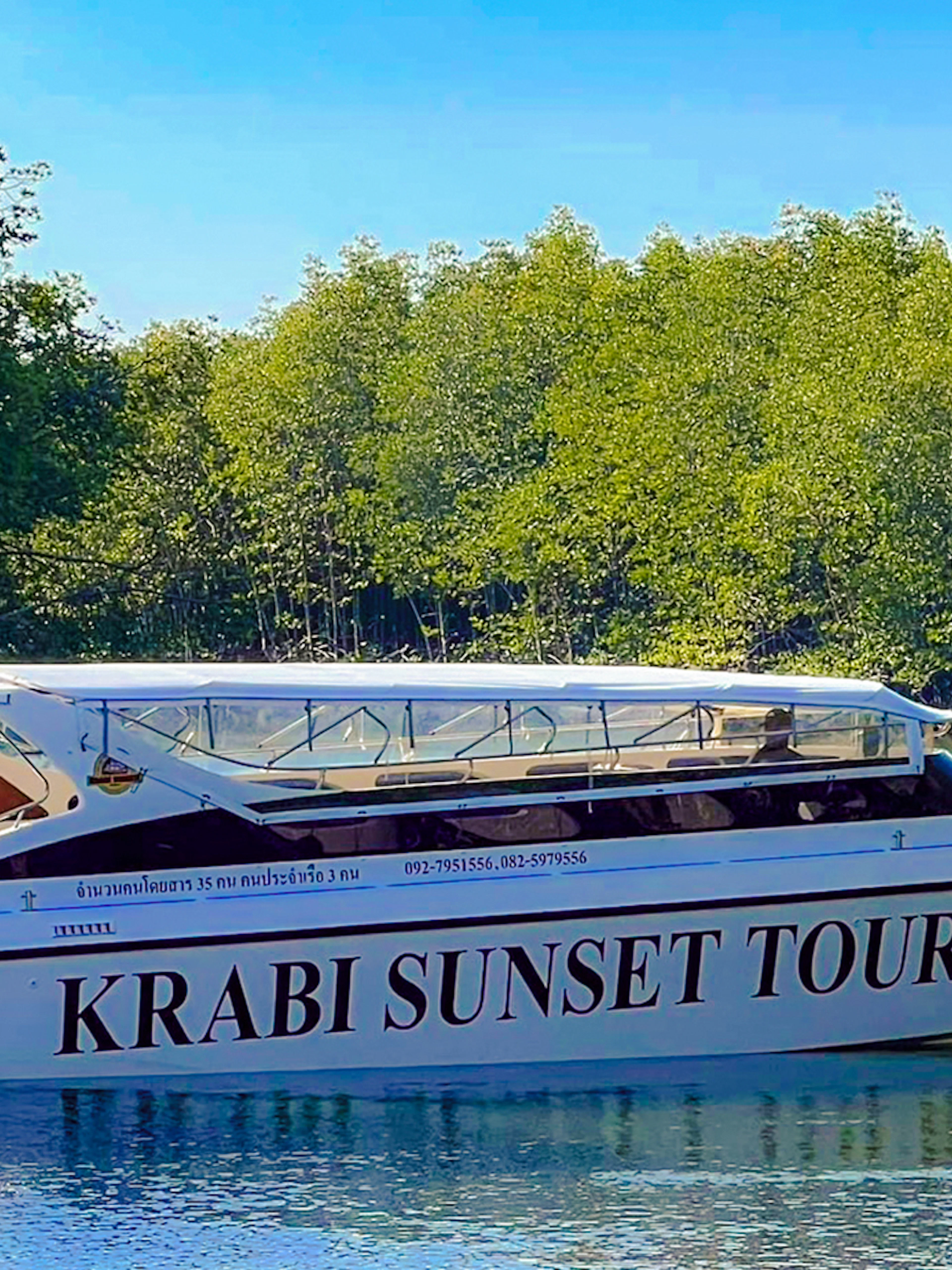 Speedboat for Krabi Sunset Tours on water near lush greenery, Phi Phi Islands.