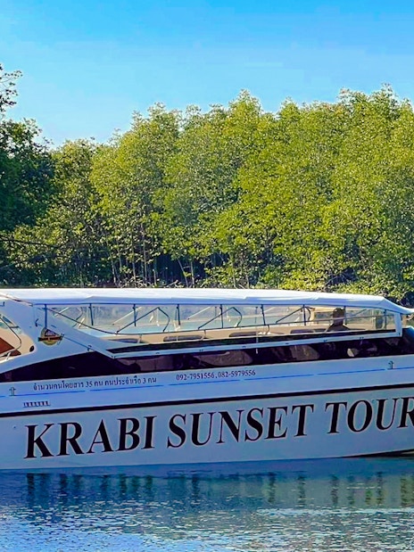 Speedboat for Krabi Sunset Tours on water near lush greenery, Phi Phi Islands.